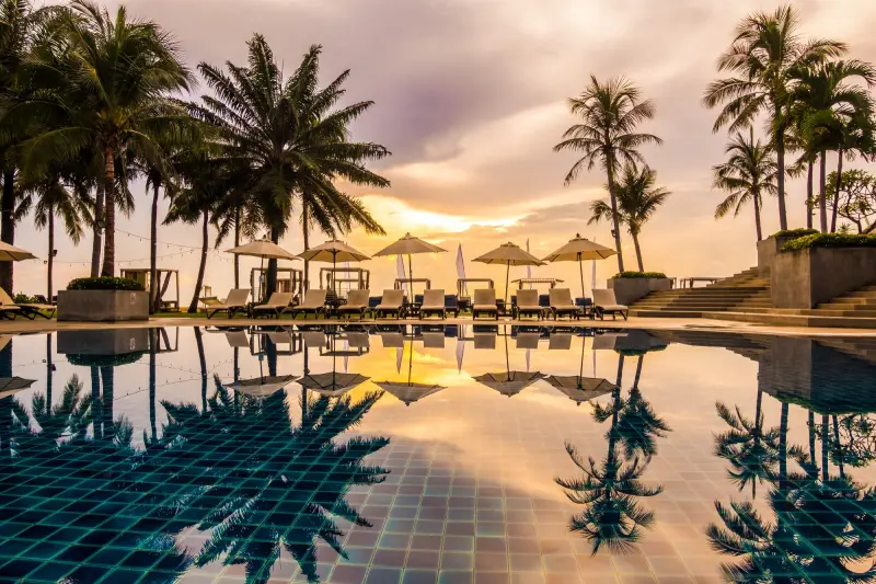 Scenic 5-star resort with infinity pool, palm trees, and beachfront view at sunset offering ultimate luxury.